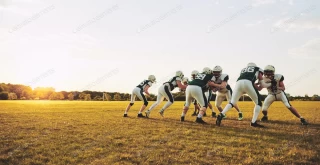 بازیکنان فوتبال آمریکایی در حال انجام تمرین دفاعی در یک زمین ورزشی