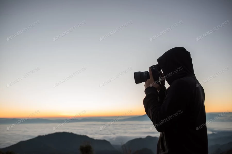 عکس استوک فردی در حال عکاسی از طلوع خورشید