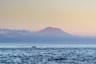 عکس کوه آتشفشان آگونگ در دورنمای دریا هنگام طلوع خورشید